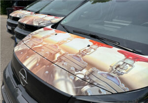 Motorhauben mehrerer Gas-Solution-Fahrzeuge nebeneinander, alle mit identischem Design beklebt