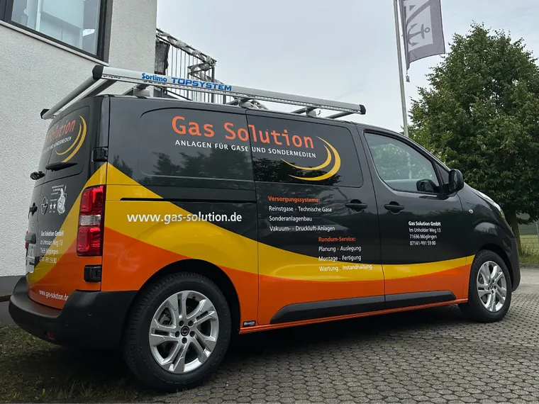 Beschrifteter Transporter von Gas Solution in Seitenansicht mit Logo, Website und Leistungsübersicht auf der Schiebetür