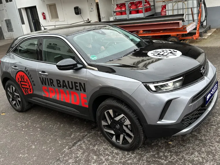 Silberner Firmenwagen von Kessler Spinde mit roter Teilbeschriftung und Slogan Wir bauen Spinde