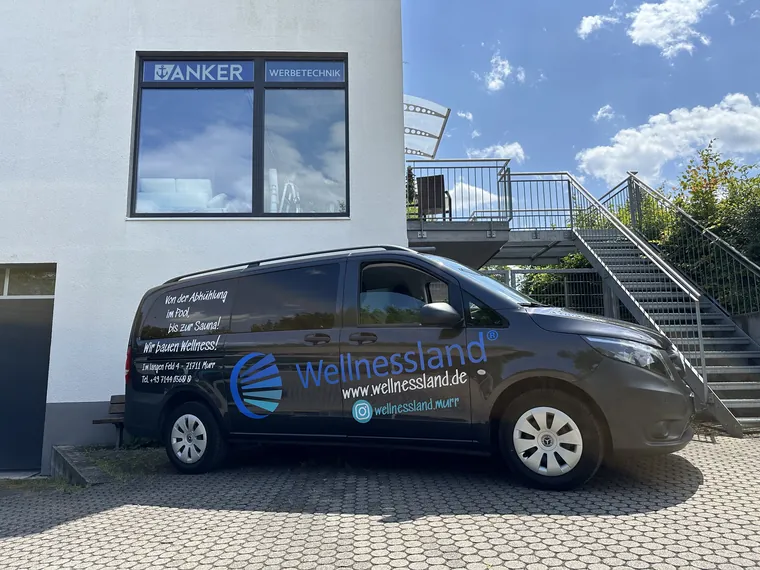 Beschrifteter Transporter von Wellnessland mit Logo, Website und Stellenanzeige auf der Schiebetür